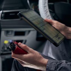 Mechanic in protective clothes sitting in the car and removing errors from the on-board computer system